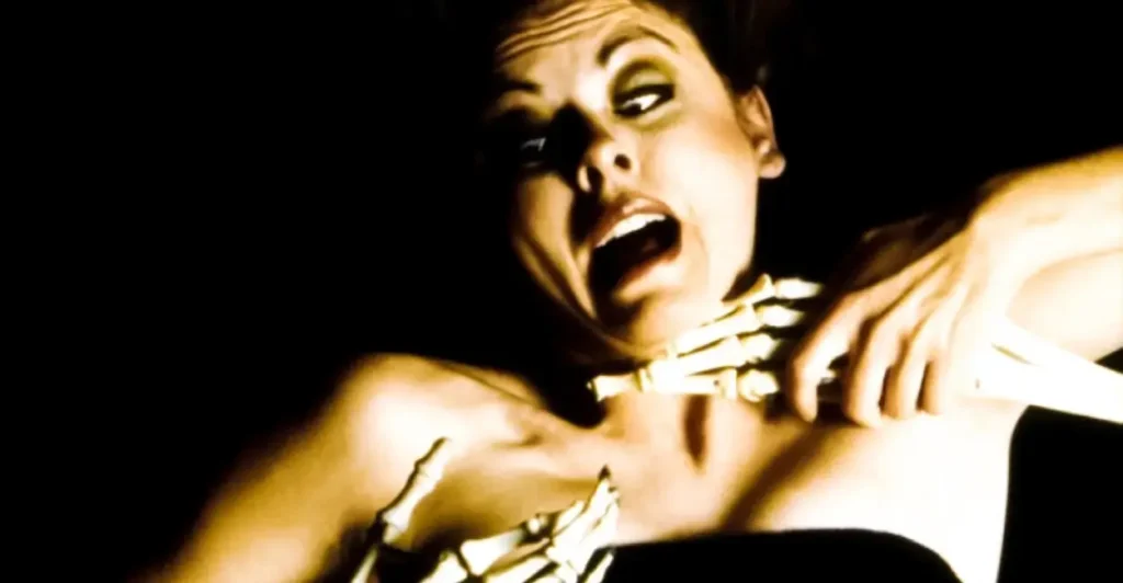 Cena do filme A Morte do Demônio (The Evil Dead, 1981), com a personagem Cheryl Williams (interpretada por Ellen Sandweiss) sendo atacada por mãos demoníacas esqueléticas, em uma das sequências mais icônicas e assustadoras do clássico cult de terror dirigido por Sam Raimi.