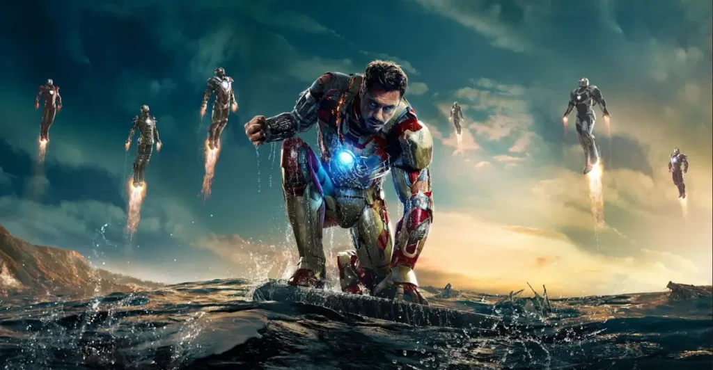 Cena do filme Homem de Ferro 3 (2013), com Tony Stark (interpretado por Robert Downey Jr.) ajoelhado em meio ao oceano com sua armadura danificada, enquanto múltiplas armaduras voam ao fundo — representando o auge da tecnologia Stark no Universo Cinematográfico da Marvel.