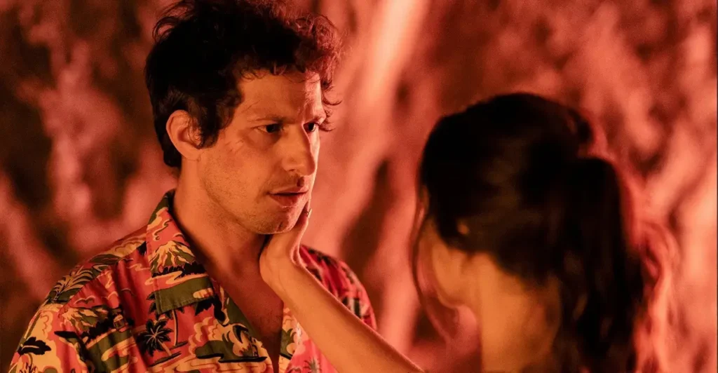 Cena do filme Palm Springs (2020), com Nyles (Andy Samberg) encarando Sarah (Cristin Milioti) enquanto ela toca seu rosto com carinho — momento tenso e emotivo que destaca o vínculo entre os protagonistas presos em um looping temporal.
