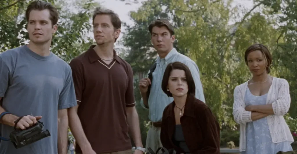 Cena do filme Pânico 2 (1997) com os personagens Mickey Altieri (Timothy Olyphant), Randy Meeks (Jamie Kennedy), Derek Feldman (Jerry O'Connell), Sidney Prescott (Neve Campbell) e Hallie McDaniel (Elise Neal) observando algo com tensão — momento que antecipa os perigos do assassino Ghostface na continuação do clássico slasher.