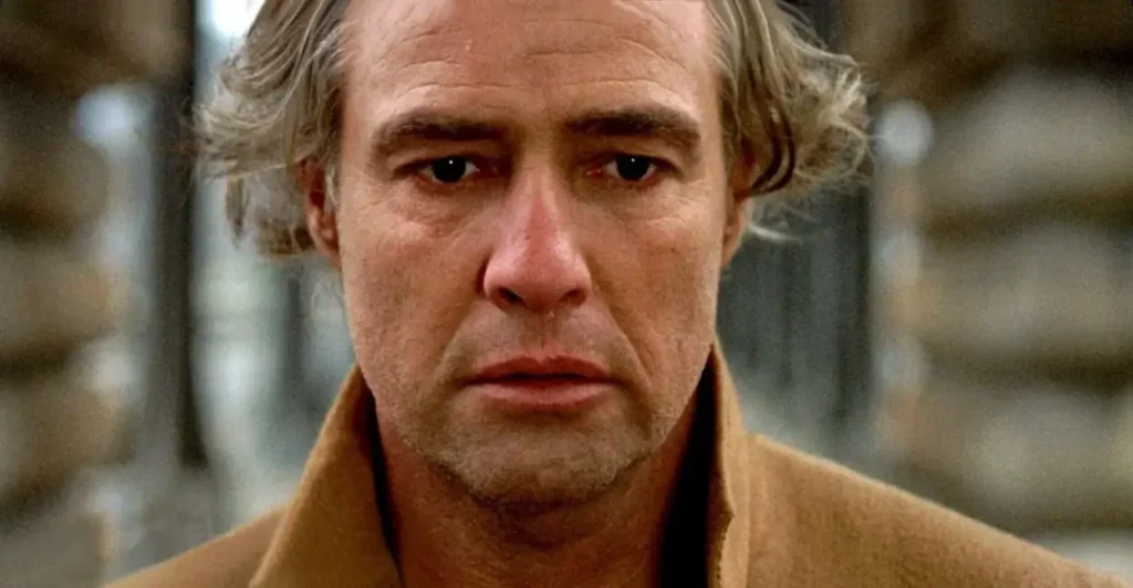 Cena marcante do filme Último Tango em Paris com close no personagem vivido por Marlon Brando, transmitindo expressão de dor e melancolia, símbolo do cinema polêmico dos anos 1970.